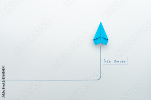 New normal concept with blue paper plane in new direction on white background photo