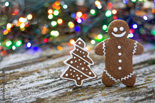 Christmas gingerbread man and tree on rustic background with colorful bokeh