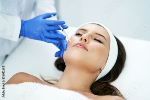 Beautiful young woman getting acid face treatment at beauty salon.