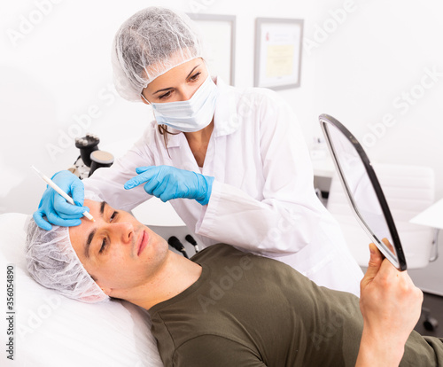 Female cosmetician consulting man before facial treatment
