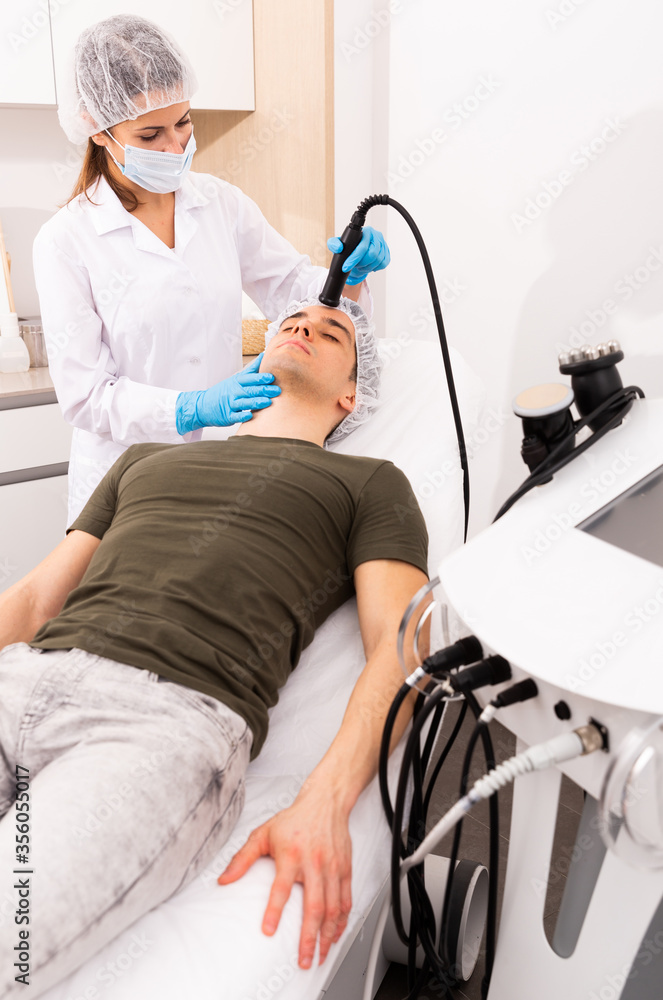 Obraz premium Woman cosmetologist giving facial electroporation procedure to male