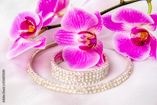 Fototapeta Naklejka Na Ścianę i Meble -  Bracelet and necklace on white fabric and purple Orchid
