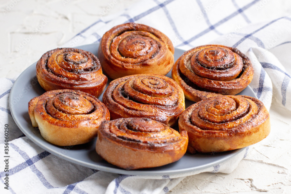 baked cinnamon buns on grey plate on light background with checkered napkin