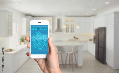 Woman using home security app indoors, closeup. Space for text