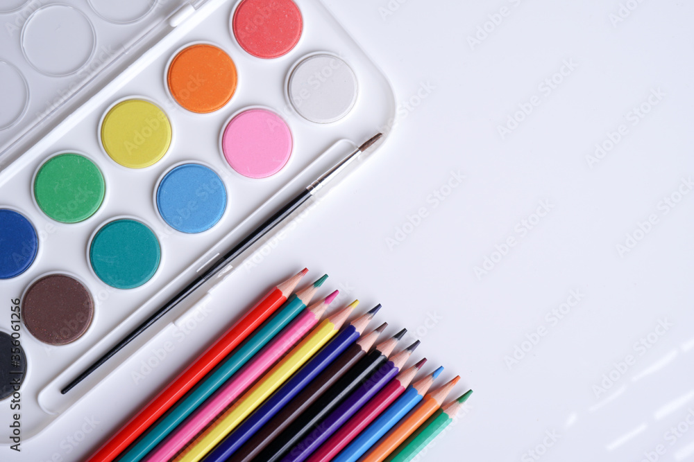 Naklejka premium Flat lay composition water color and brush and color pencils isolation on white background. Empty space for text.