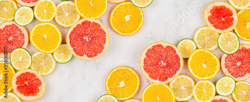 Creative background made of summer tropical fruits with grapefruit  orange  tangerine  lemon  lime on white marble background. Food concept. Flat lay  top view  copy space  mockup