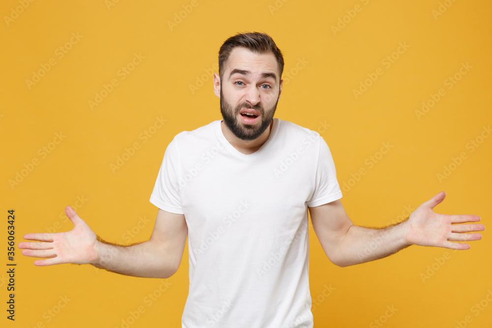 Perplexed bewildered young bearded man guy in white casual t-shirt posing isolated on yellow background studio portrait. People sincere emotions lifestyle concept. Mock up copy space. Spreading hands. Perplexed bewildered young bearded man guy in white casual t-shirt posing isolated on yellow background studio portrait. People sincere emotions lifestyle concept. Mock up copy space. Spreading hands.