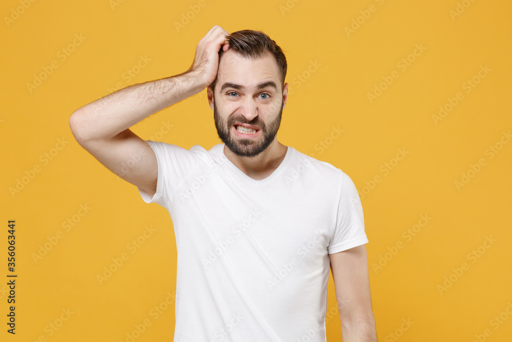 Preoccupied young bearded man guy in white casual t-shirt posing isolated on yellow wall background studio portrait. People sincere emotions lifestyle concept. Mock up copy space. Put hand on head. Preoccupied young bearded man guy in white casual t-shirt posing isolated on yellow wall background studio portrait. People sincere emotions lifestyle concept. Mock up copy space. Put hand on head.