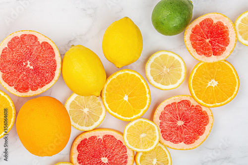 Creative background made of summer tropical fruits with grapefruit  orange  tangerine  lemon  lime on white marble background. Food concept. Flat lay  top view  copy space  mockup