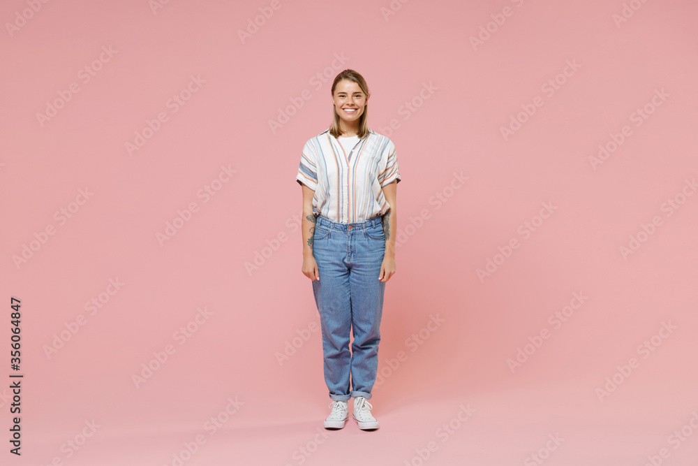 Smiling young blonde woman girl in casual striped shirt posing isolated on pastel pink wall background studio portrait. People sincere emotions lifestyle concept. Mock up copy space. Looking camera. Smiling young blonde woman girl in casual striped shirt posing isolated on pastel pink wall background studio portrait. People sincere emotions lifestyle concept. Mock up copy space. Looking camera.