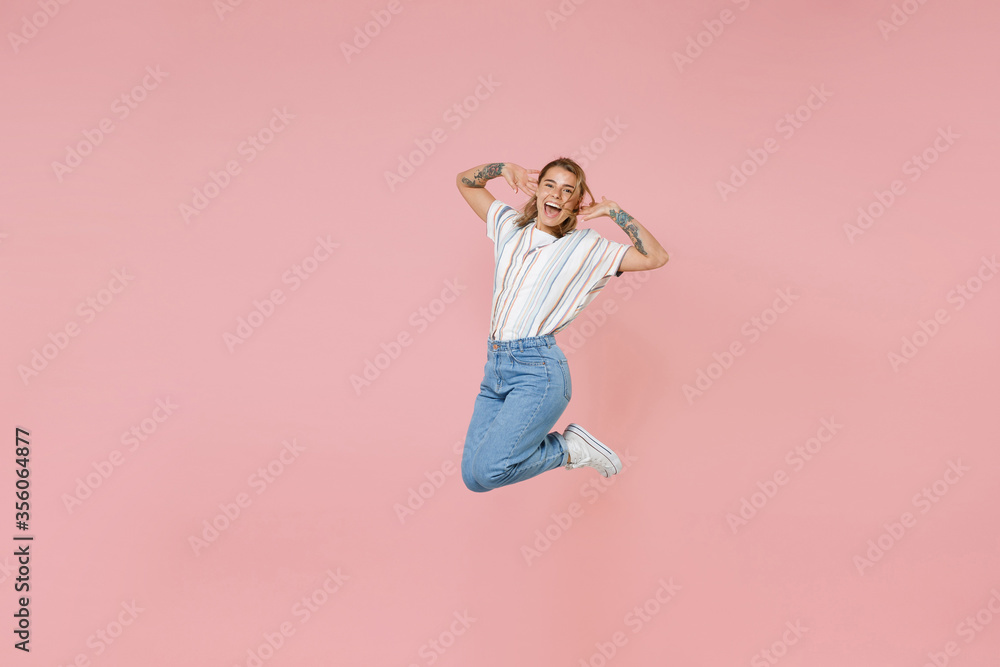 Cheerful young blonde woman girl in casual striped shirt posing isolated on pastel pink background studio portrait. People emotions lifestyle concept. Mock up copy space. Jumping, put hands on head. Cheerful young blonde woman girl in casual striped shirt posing isolated on pastel pink background studio portrait. People emotions lifestyle concept. Mock up copy space. Jumping, put hands on head.