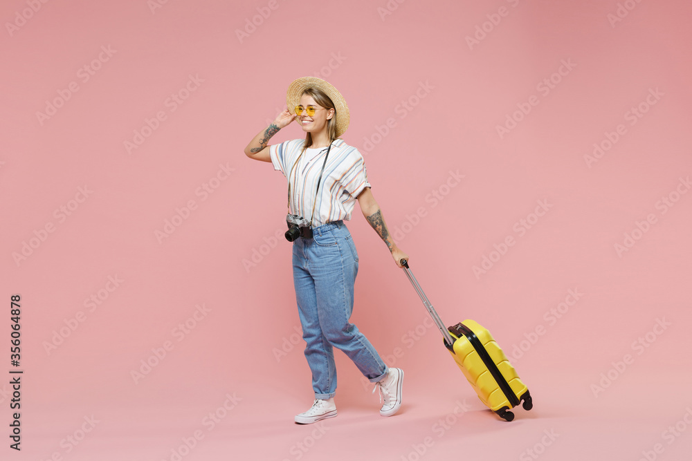 Smiling girl in striped shirt glasses hat photo camera isolated on pink background. Passenger traveling abroad to travel on weekends getaway. Air flight journey concept. Hold suitcase, looking aside. Smiling girl in striped shirt glasses hat photo camera isolated on pink background. Passenger traveling abroad to travel on weekends getaway. Air flight journey concept. Hold suitcase, looking aside.