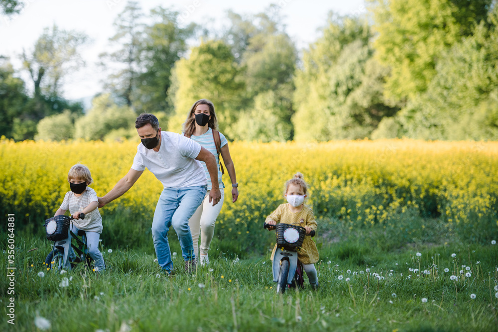Family with two small children and face masks on cycling trip in countryside. Family with two small children and face masks on cycling trip in countryside.