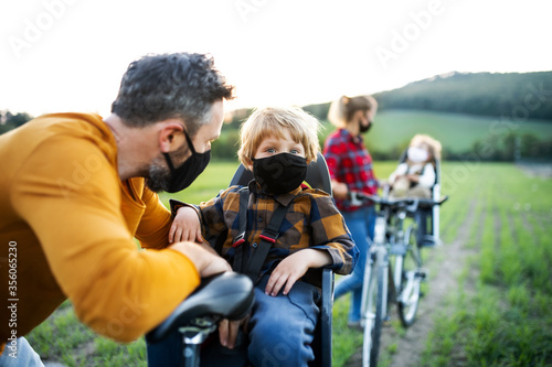 Family with two small children on cycling trip, wearing face masks.