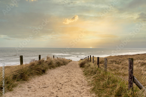 Sunset over the North Sea with a view from a sandy dune path towards the sea near Noordwijk, Netherlands