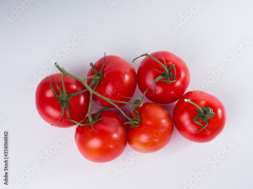 Fresh red tomatoes on a branch on a white background. Studio photography © Евгений Казанцев