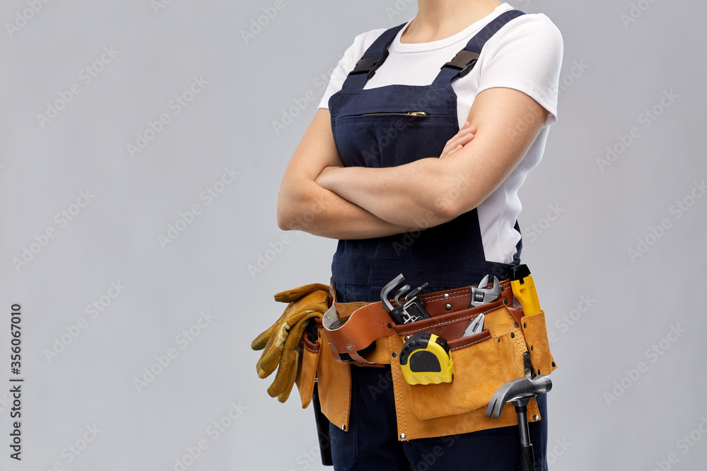 repair, construction and building concept - woman or builder with working tools on belt over grey background repair, construction and building concept - woman or builder with working tools on belt over grey background