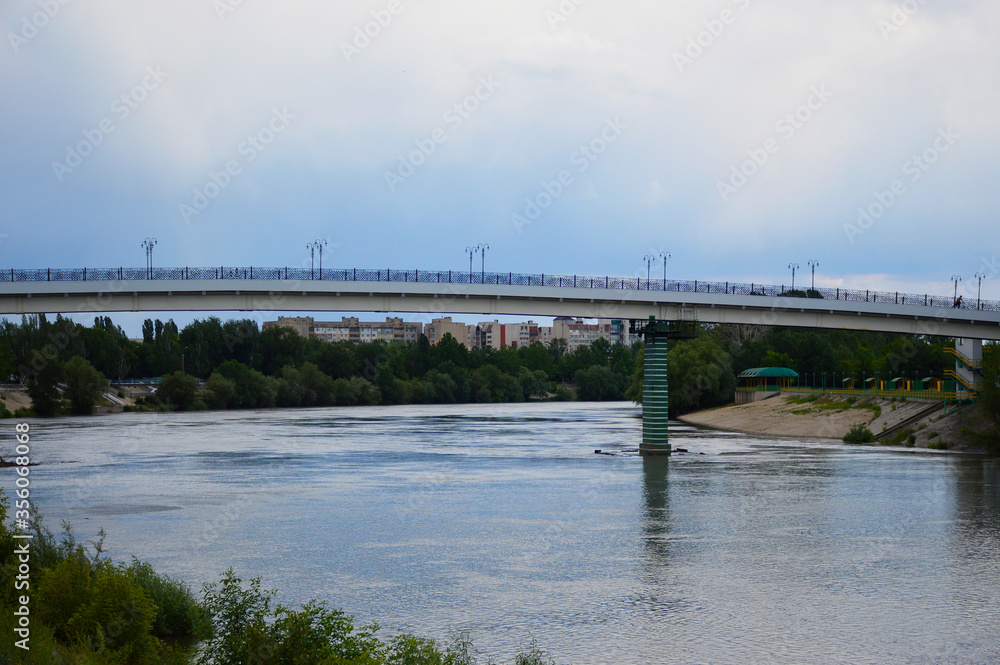 bridge over the river in the city. on the right is a small beach, in the background are multi-storey buildings bridge over the river in the city. on the right is a small beach, in the background are multi-storey buildings