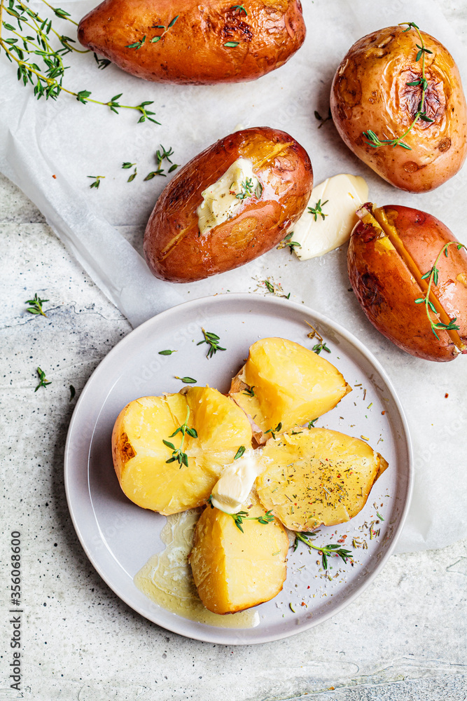 Baked potatoes with butter and thyme on gray plate, top view. Baked potatoes with butter and thyme on gray plate, top view.