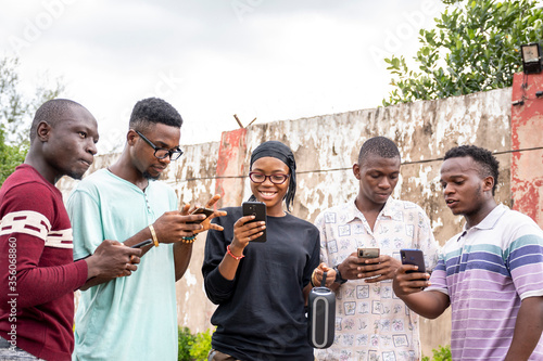 group of young africans using their phones, hanging out together, students leisure on campus © Confidence