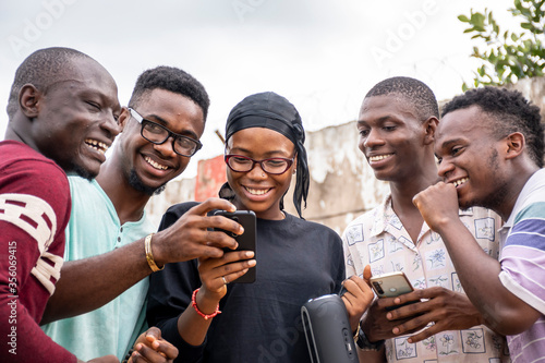 a group of young africans using their phones, hanging out together, students leisure on campus, viewing content on a phone together
