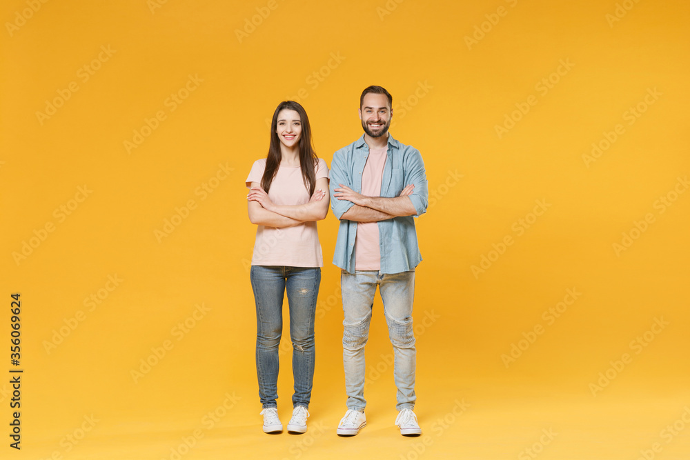 Smiling young couple two friends guy girl in pastel blue casual clothes posing isolated on yellow wall background studio portrait. People lifestyle concept. Mock up copy space. Holding hands crossed. Smiling young couple two friends guy girl in pastel blue casual clothes posing isolated on yellow wall background studio portrait. People lifestyle concept. Mock up copy space. Holding hands crossed.