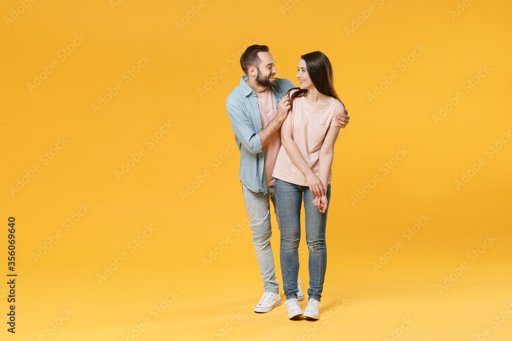 Smiling young couple two friends guy girl in pastel blue casual clothes posing isolated on yellow wall background studio portrait. People lifestyle concept. Mock up copy space. Looking at each other. Smiling young couple two friends guy girl in pastel blue casual clothes posing isolated on yellow wall background studio portrait. People lifestyle concept. Mock up copy space. Looking at each other.