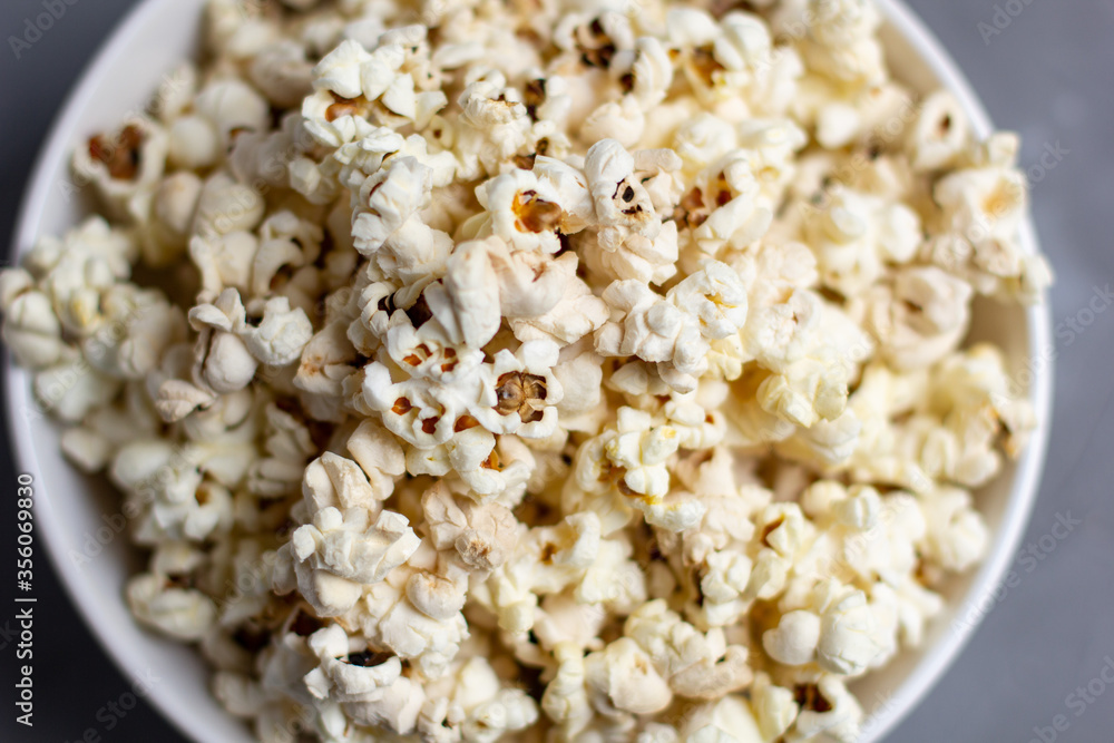 Popcorn in white bowl on grey table. Top view with copyspace Popcorn in white bowl on grey table. Top view with copyspace