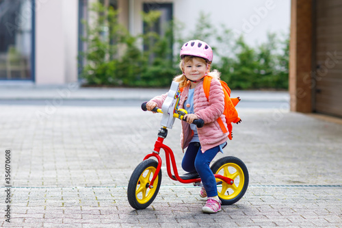 Little happy toddler girl on first day going to playschool daycare. Healthy baby on pushing bike to nursery school. Back to kindergarten after quarantine time from corona and covid 19 pandemic disease