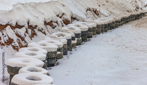 Old tires of cars installed along the highway rally in winter powdered snow