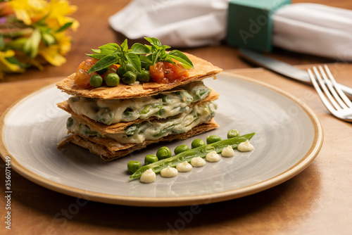puff pastry stuffed with pea cream and garnished with salmon tomato and basil