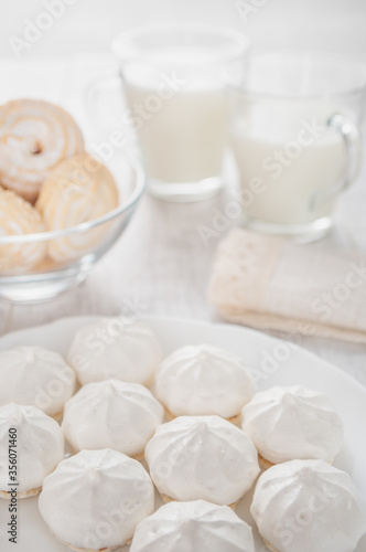 White round marshmallows, two cups of milk, cookies in powdered sugar.