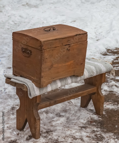 Wooden chest on a wooden bench amid a spring snow