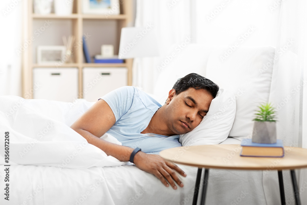 people, bedtime and rest concept - indian man with health tracker sleeping in bed at home people, bedtime and rest concept - indian man with health tracker sleeping in bed at home