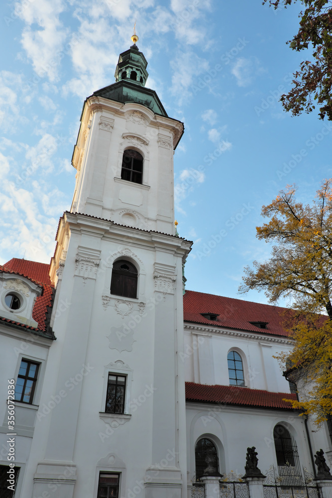 The bell tower of the Strahov Monastery against the blue sky in autumn.