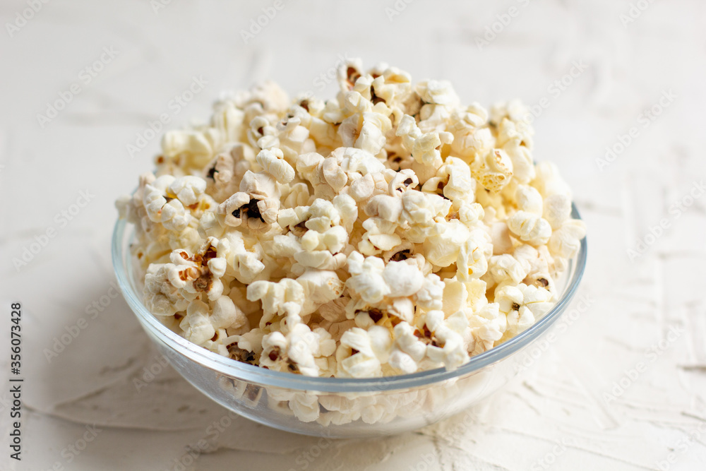 popcorn in a transparent glass bowl on white table popcorn in a transparent glass bowl on white table