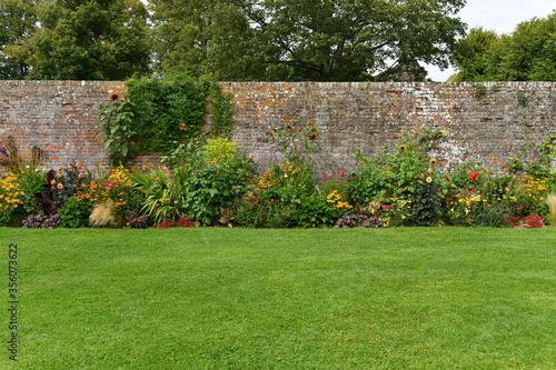 Foto Garden Lawn, Flower Bed and Old Brick Wall
