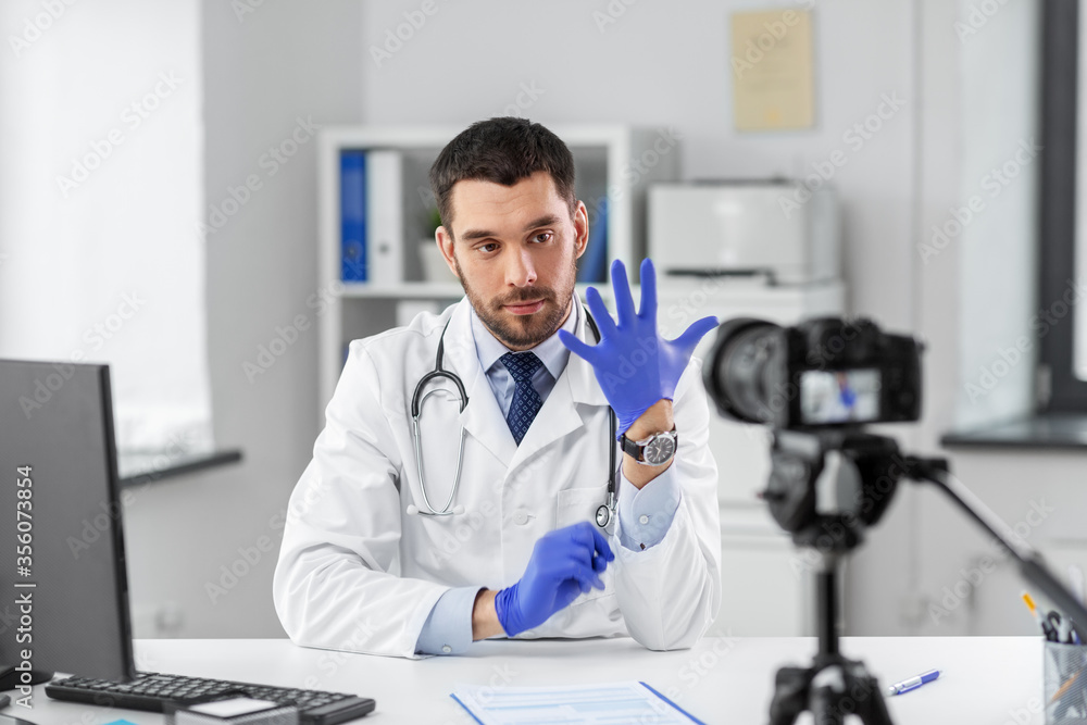 healthcare, medicine and blogging concept - male doctor with camera and gloves recording video blog at hospital healthcare, medicine and blogging concept - male doctor with camera and gloves recording video blog at hospital