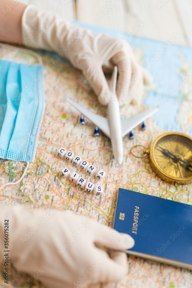 Obraz premium Corona virus pandemic in travel industry. travel agency working table. map, toy plane, compass, face mask and trip planning after quarantine restrictions due to epidemic covid corona virus. Tourism