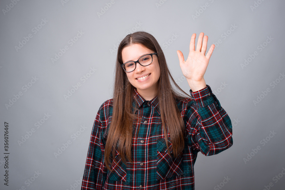 Photo of young cute girl saying Hello over white wall and looking at the camera. Photo of young cute girl saying Hello over white wall and looking at the camera.