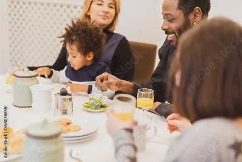 Happy interracial family with little children having breakfast in the morning, moments of daily life with Caucasian mother, African father and mixed-race children, vintage filter