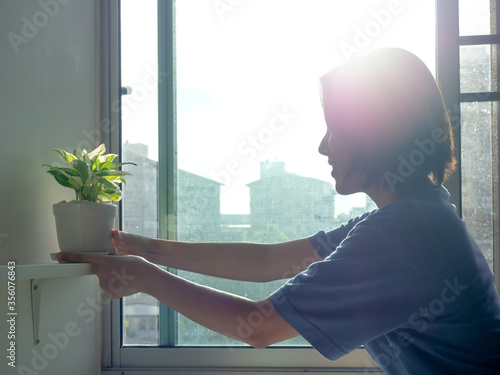 Woman holding green plants in pot at home.