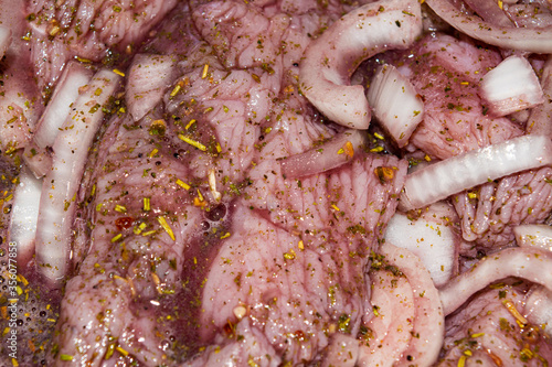 Turkey meat cut into pieces and marinated in red wine with onions and spices. Close-up, surface texture.