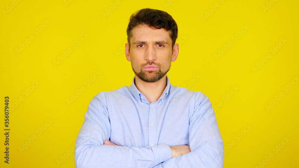 Serious bearded man with hands on his chest is looking at the camera. Handsome guy in a light blue shirt on a yellow background with copyspace. Place for text or product Serious bearded man with hands on his chest is looking at the camera. Handsome guy in a light blue shirt on a yellow background with copyspace. Place for text or product