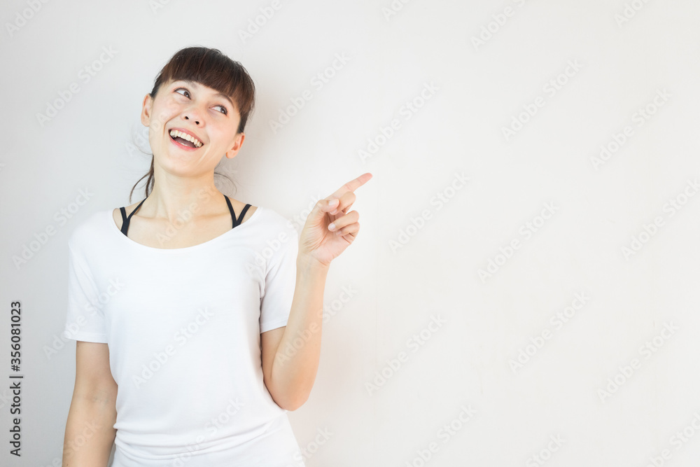 Young asian woman smiling and pointing finger on copy space white background. Young asian woman smiling and pointing finger on copy space white background.