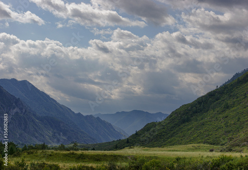 Altai mountains near the Katun river on a background of clouds. Green mountains and valley. Altai. Siberia.