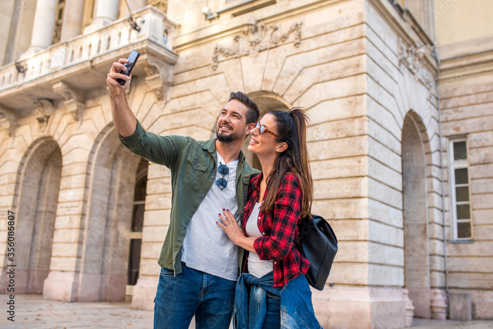 A happy couple taking a selfie in while sightseeing ion a European city