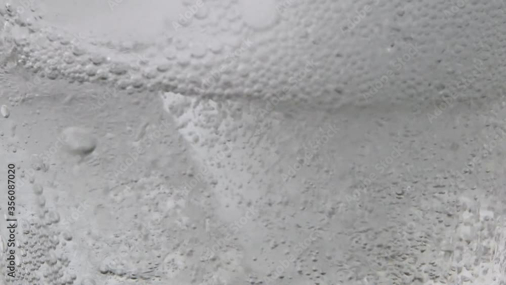 The motion of air bubbles of mineral carbonated water with ice in clear glass. The motion of air bubbles of mineral carbonated water with ice in clear glass.