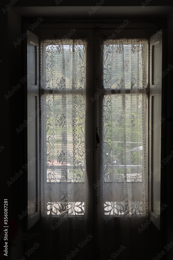 Old Wooden closed Window with a white Curtain