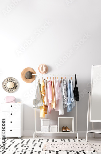 Rack with stylish women's clothes and mirror indoors. Interior design © New Africa